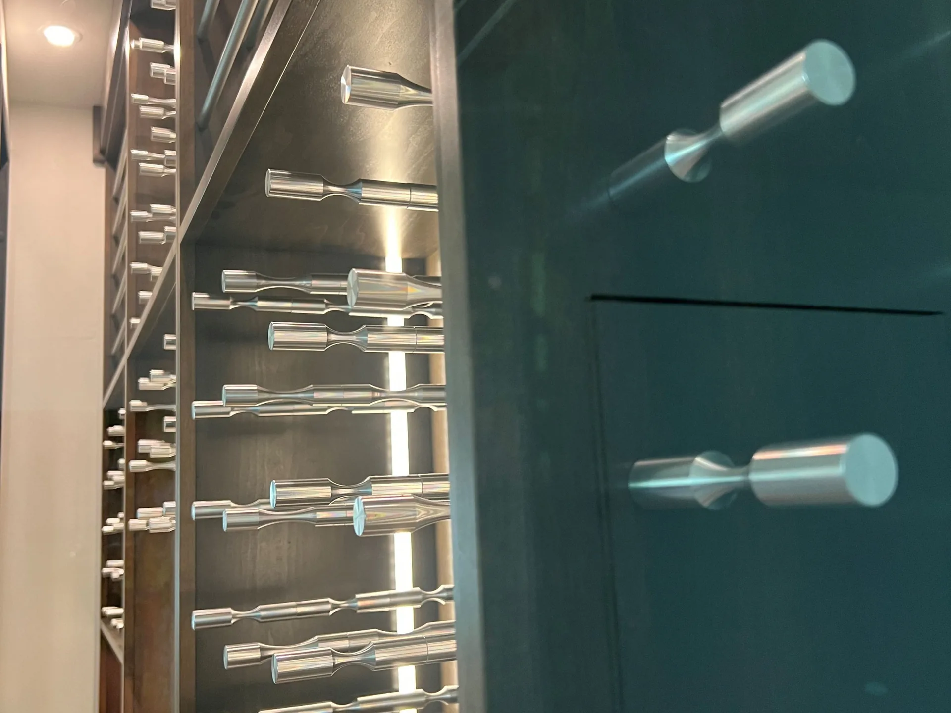 Close view of brushed metal pegs and backlit shelving