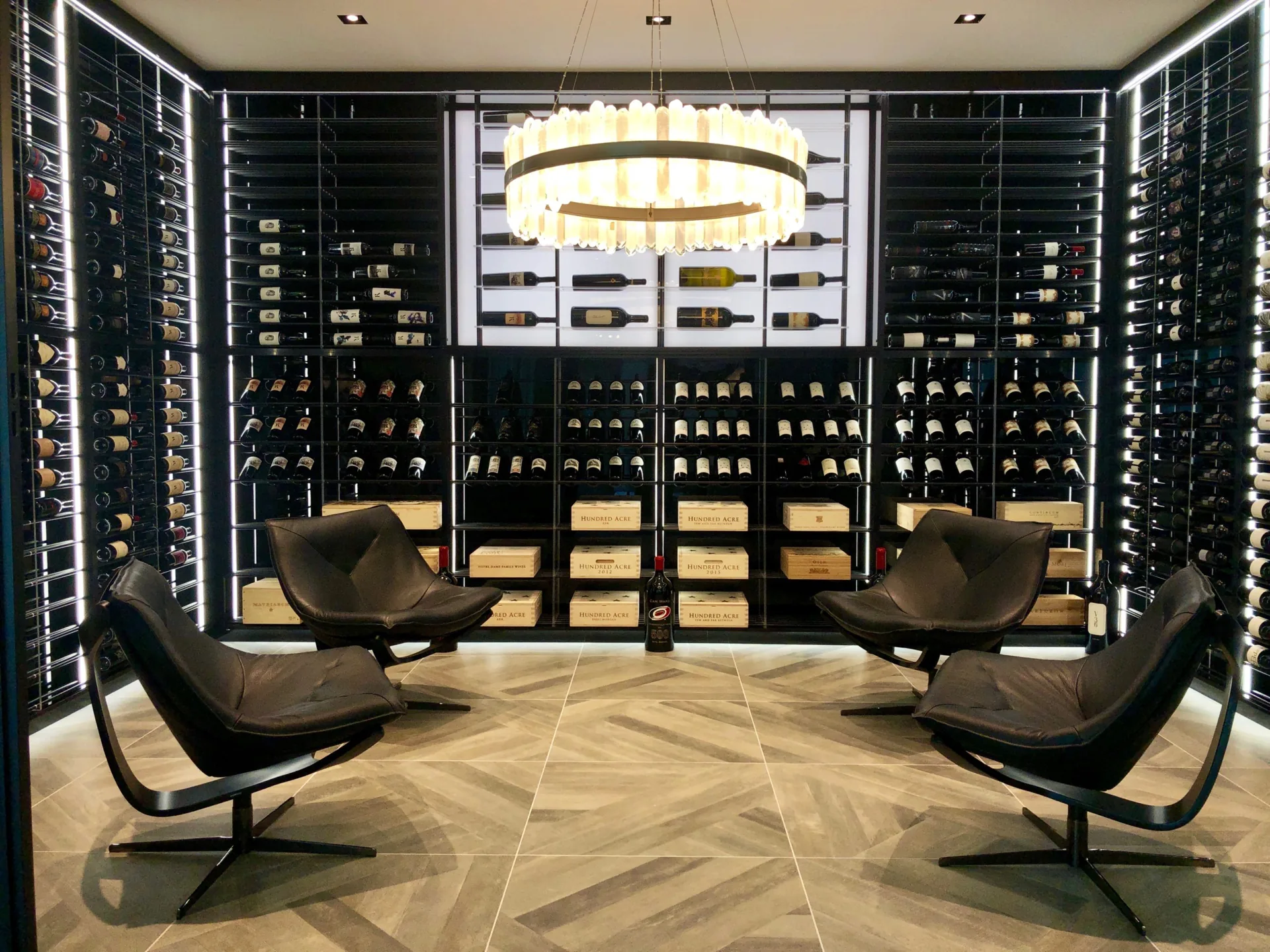 Private wine room with floor-to-ceiling racking, a chandelier and two leather chairs